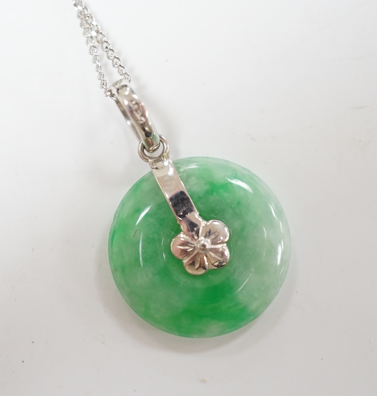A modern 14k white metal and jade set disc pendant, 18mm, on a 9ct white gold chain, 42cm, gross weight 4.3 grams.